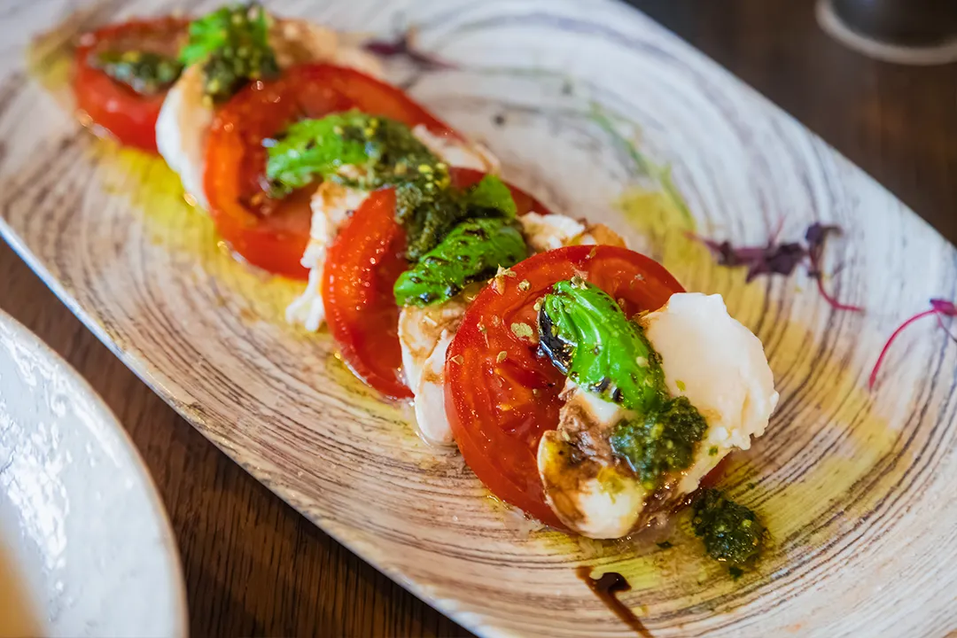 Traditional Caprese salad with fresh mozzarella, tomatoes and basil pesto served at Little Italy in York