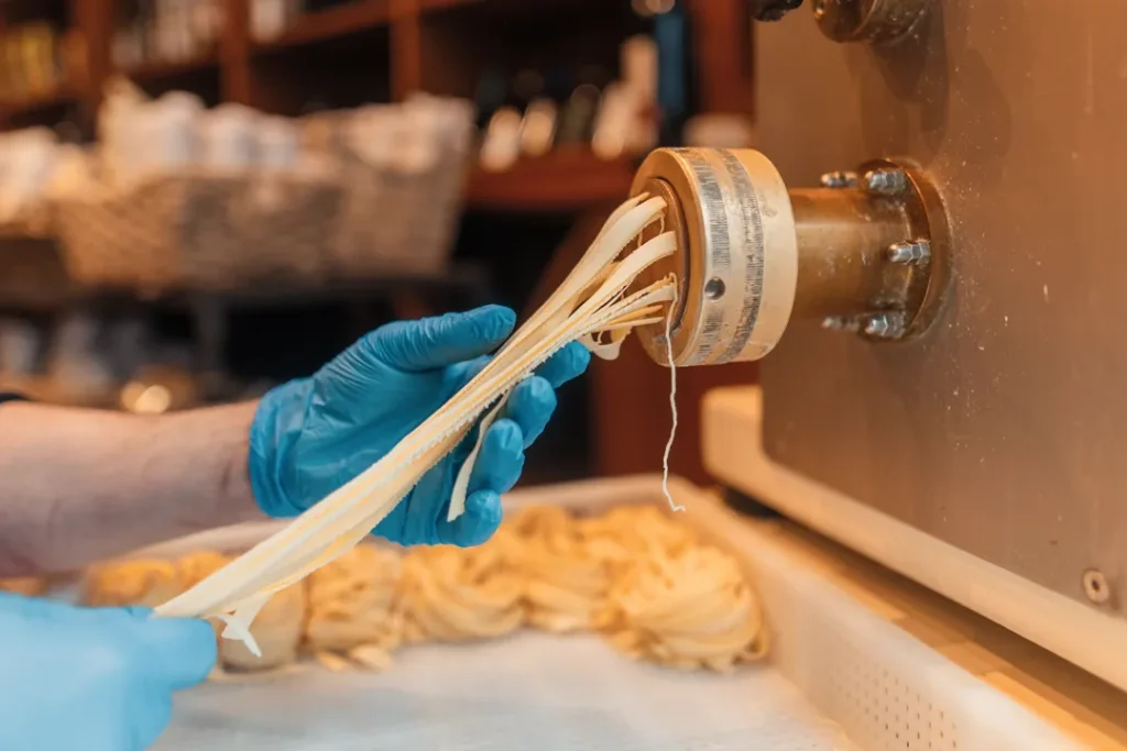 Fresh homemade tagliatelle being made using a traditional pasta machine at Little Italy York